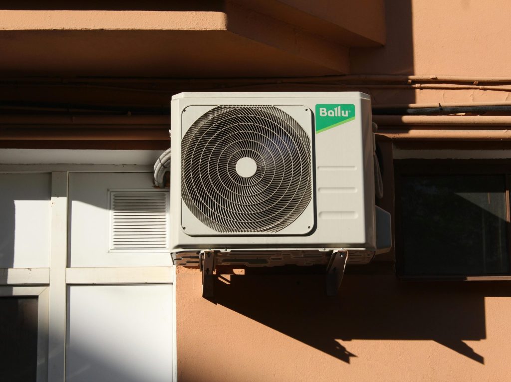 A Ballu air conditioner condenser unit mounted on a building exterior, showcasing modern HVAC technology.