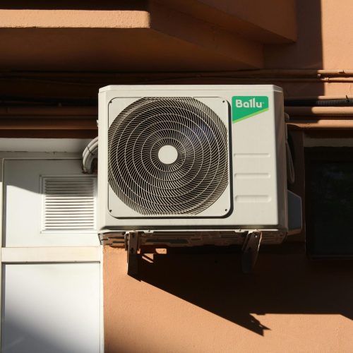 pexels-photo-24828656-24828656 A Ballu air conditioner condenser unit mounted on a building exterior, showcasing modern HVAC technology.